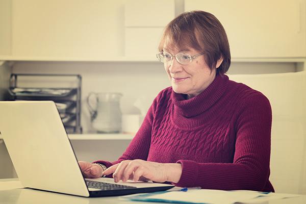 一个微笑的女人在笔记本电脑上打字.